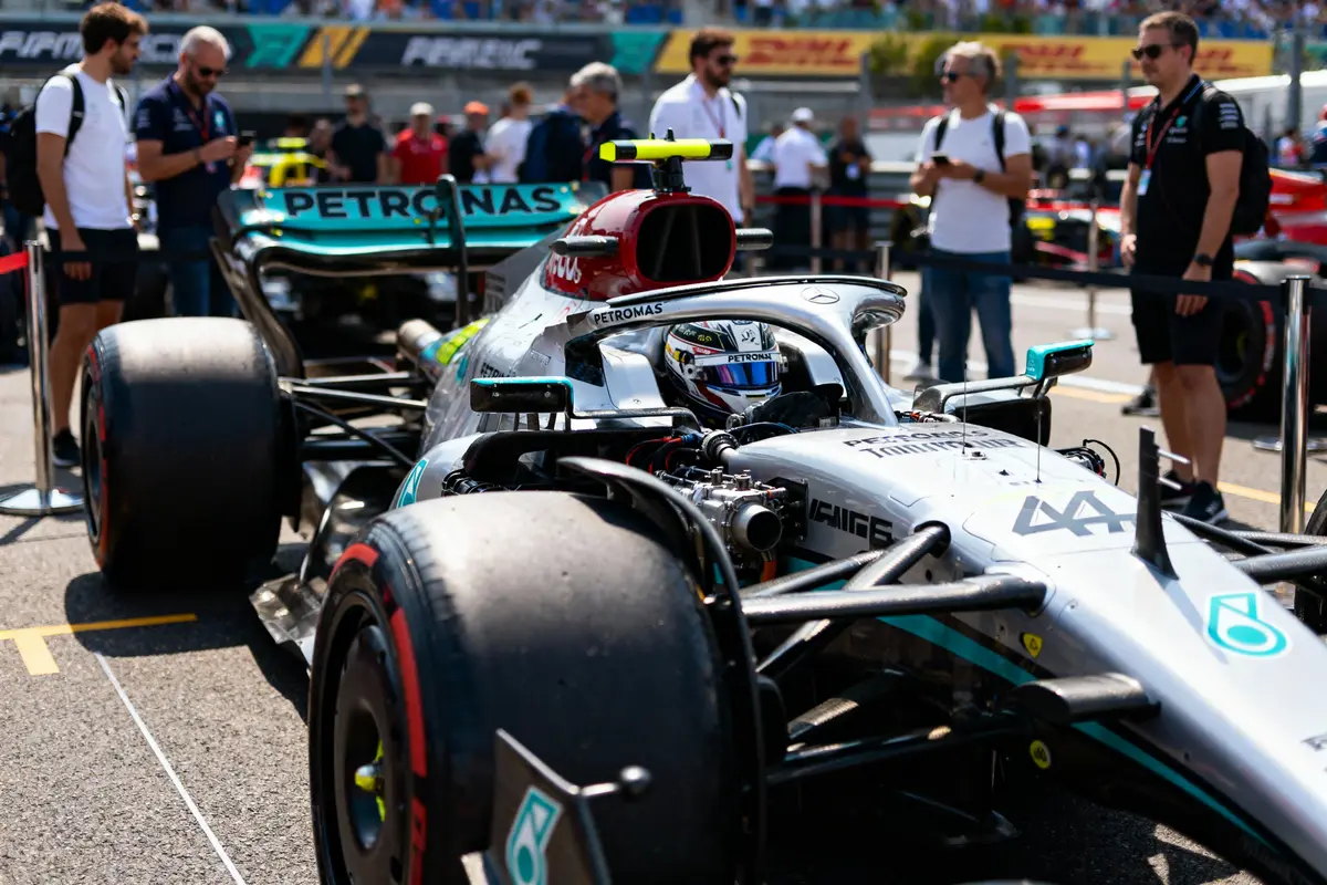 Voiture de Formule 1 Mercedes sur la grille, entourée de spectateurs et de membres de l'équipe.