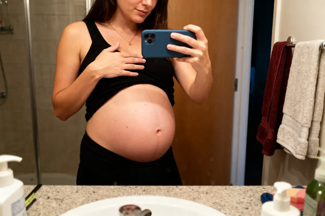 Femme enceinte prenant un selfie montrant ventre gonflé sous la poitrine chez la femme