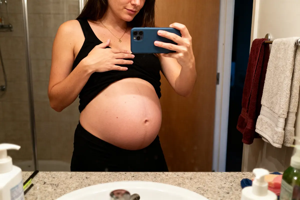 Femme enceinte prenant un selfie montrant ventre gonflé sous la poitrine chez la femme