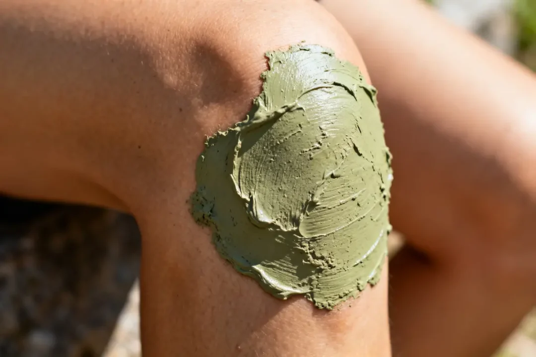 Cataplasme d'argile verte appliqué sur un genou pour soulager douleurs et inflammations